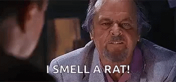 Grey-haired man in a striped jacket scowling across a table with the caption 'I smell a rat!'